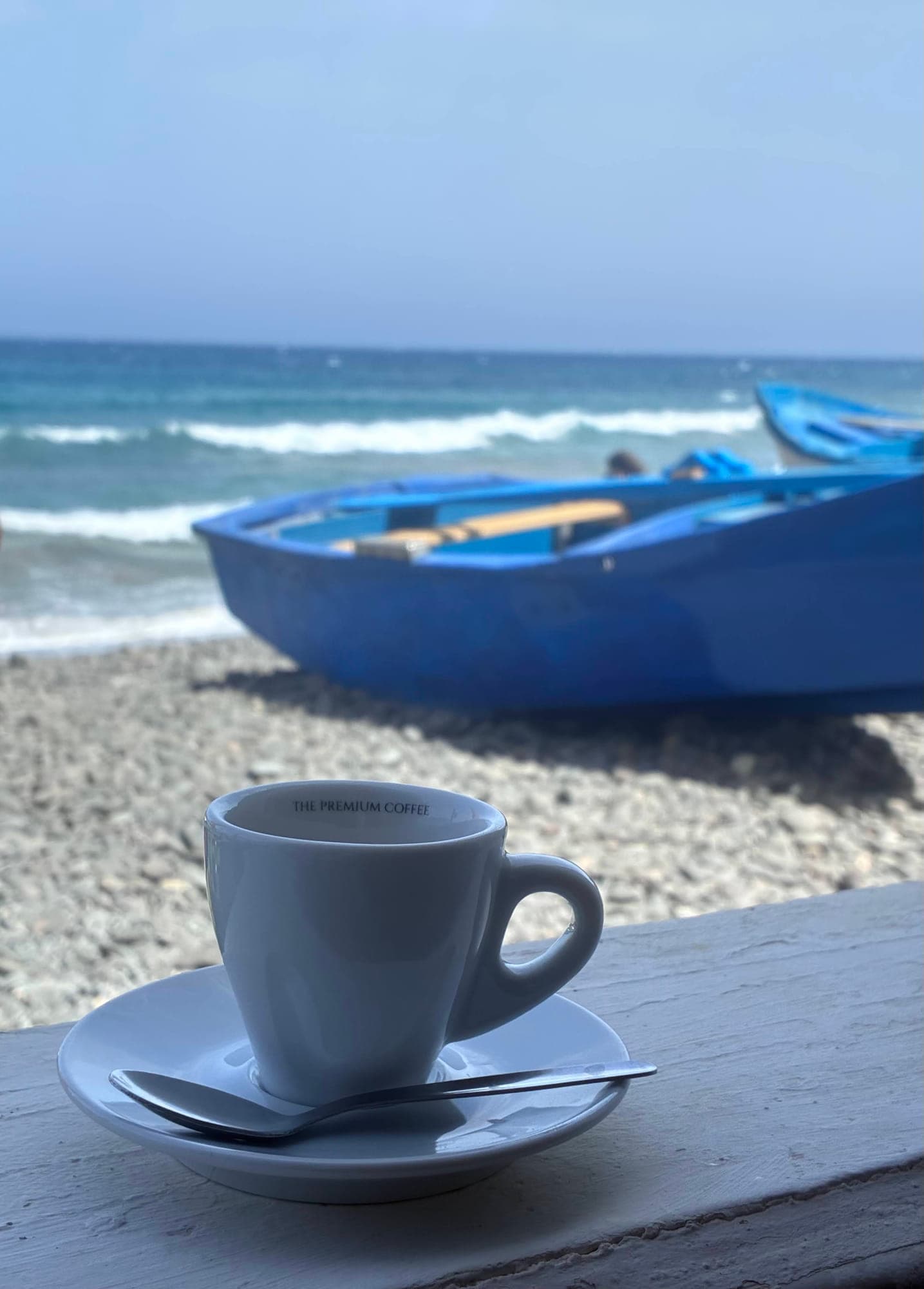Morning coffee with a blue boat on the beach
